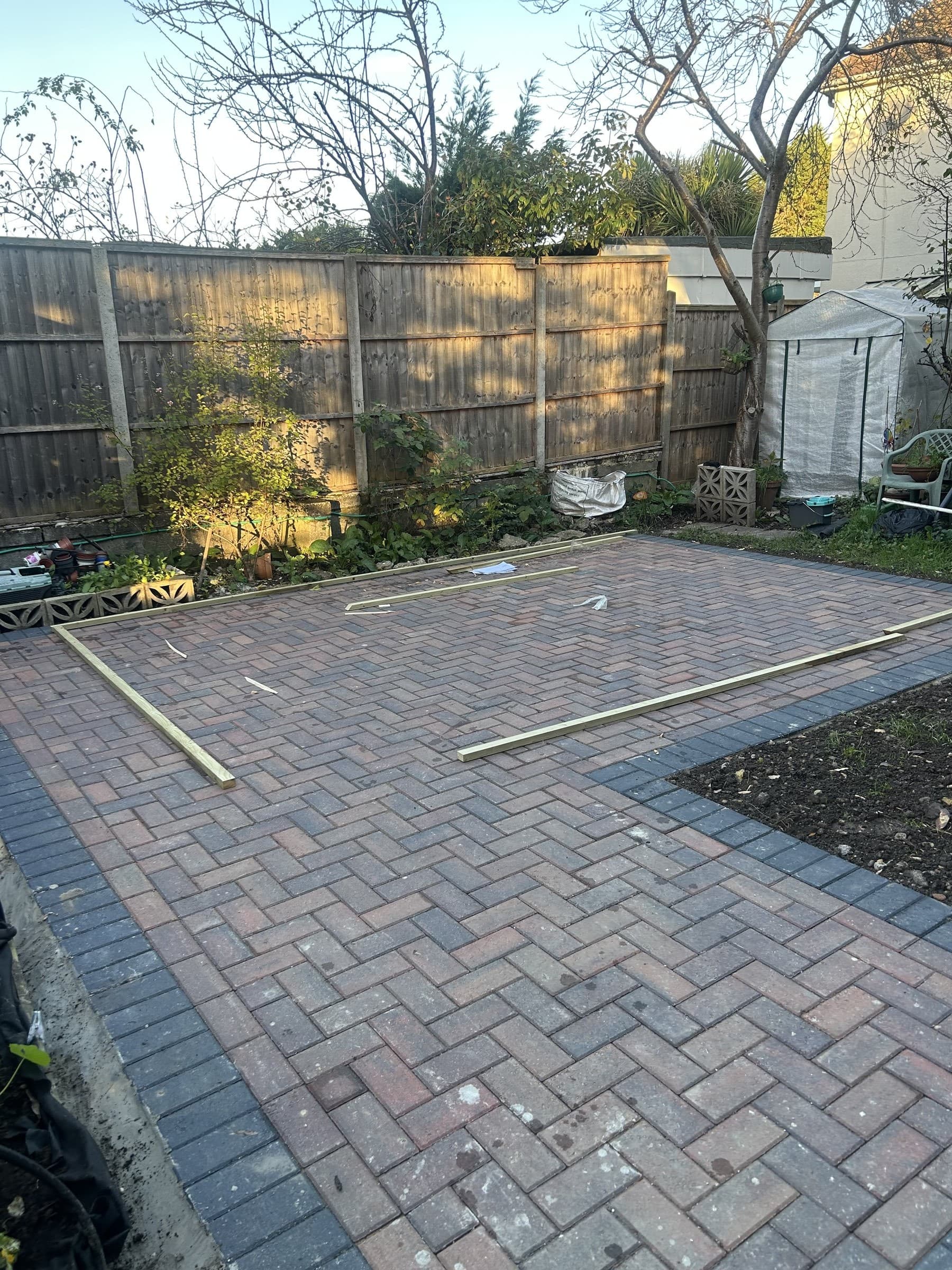 Empty garden plot with herringbone brick paving, before a garden summerhouse is built