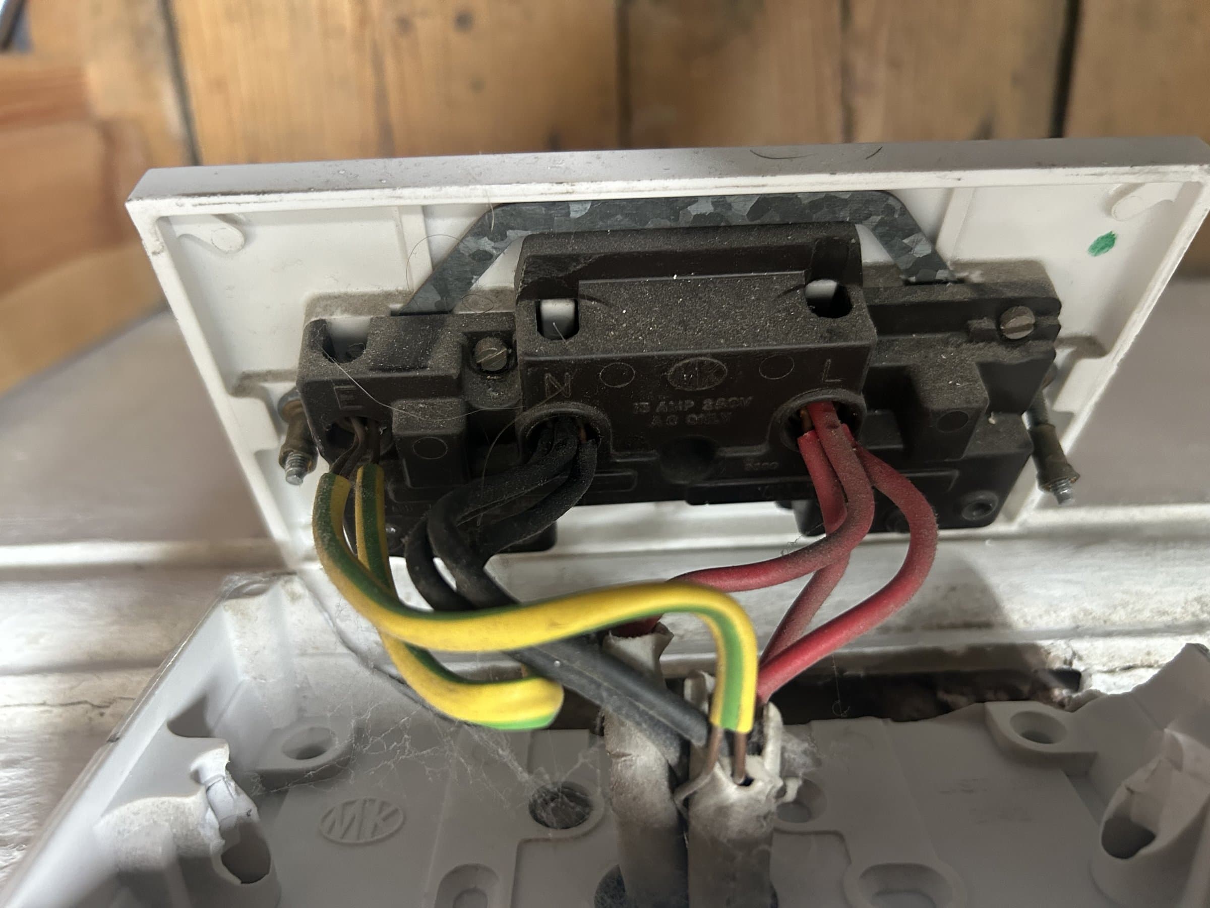 Old double socket and switch faceplate removed, exposing the wiring before replacement