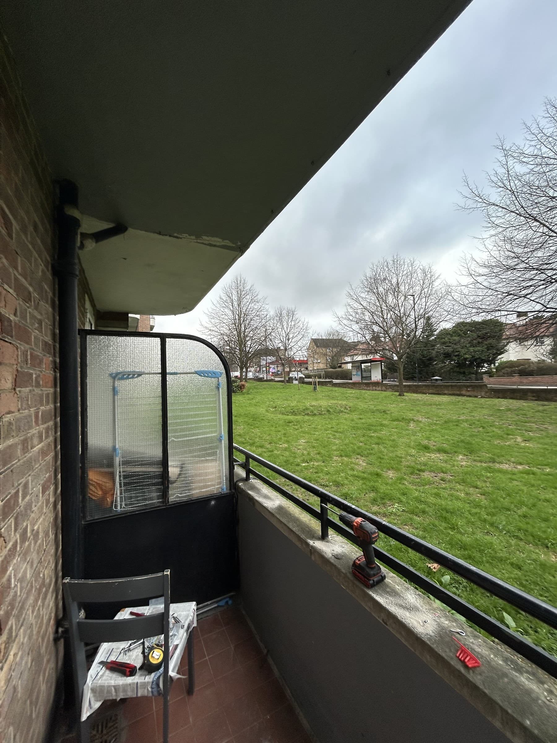 Balcony railing with tools and an incomplete safety net panel before installation