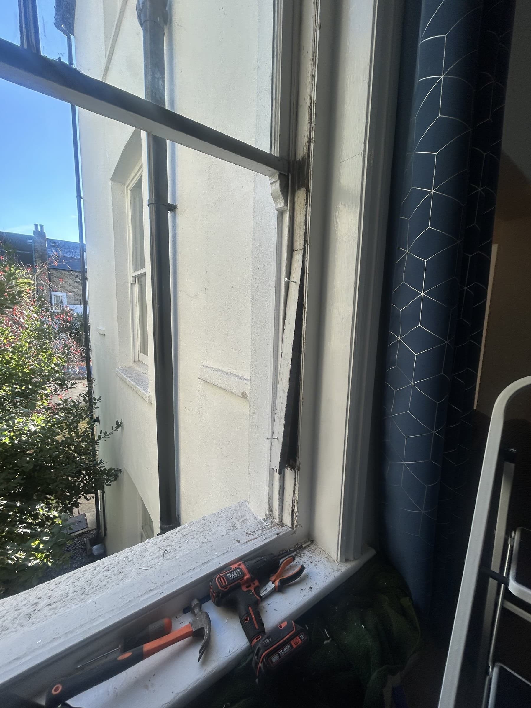 Damaged sash window frame corner with worn cord before replacement