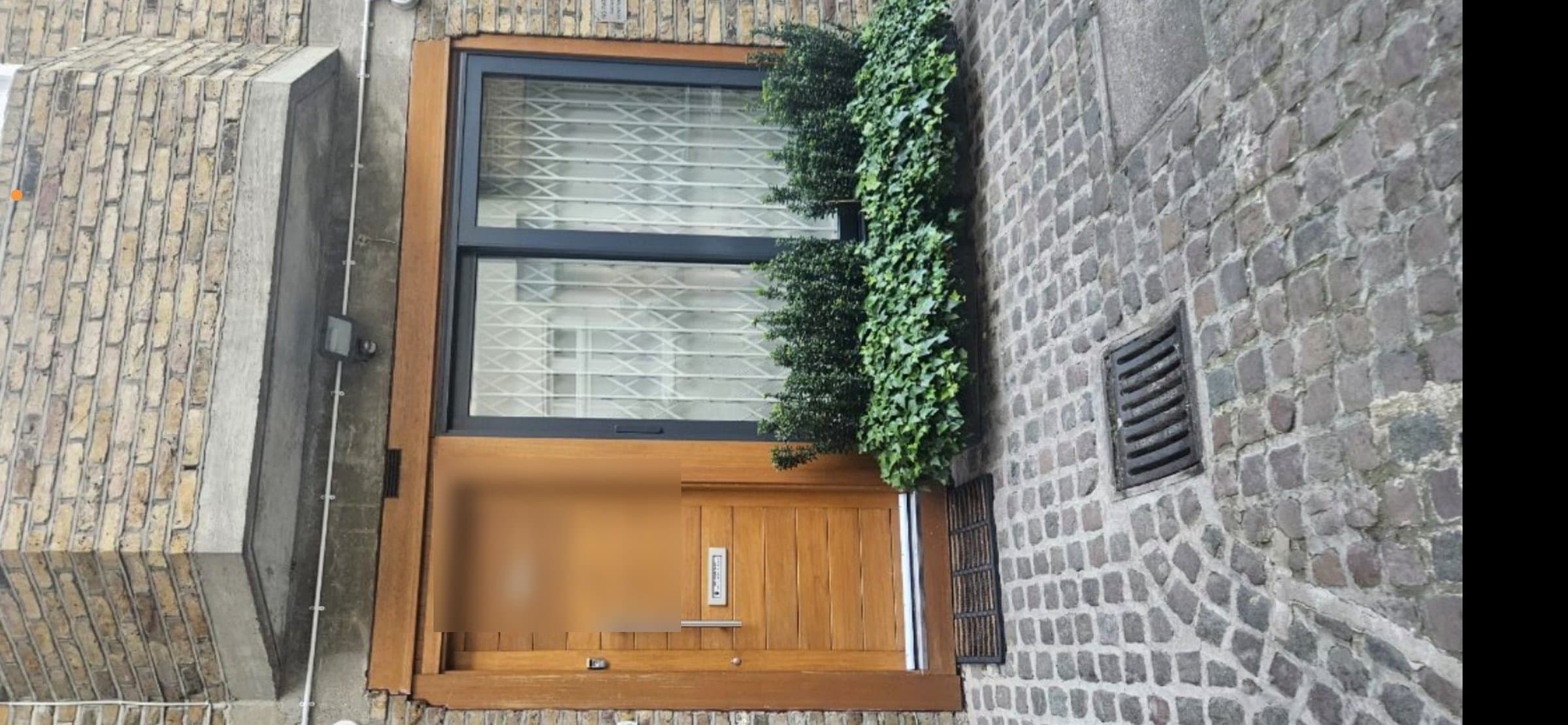 Wooden front door with a weathered, worn varnish finish before refinishing, door number blurred for privacy