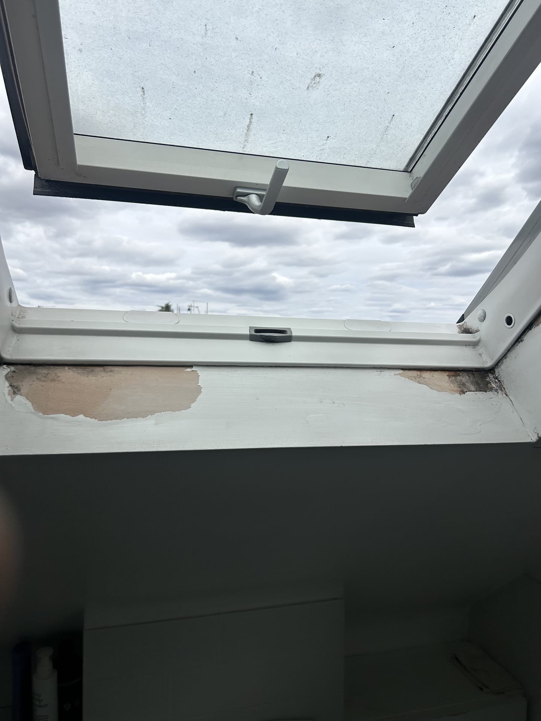 Window frame corner with chipped paint and exposed bare plaster before repair