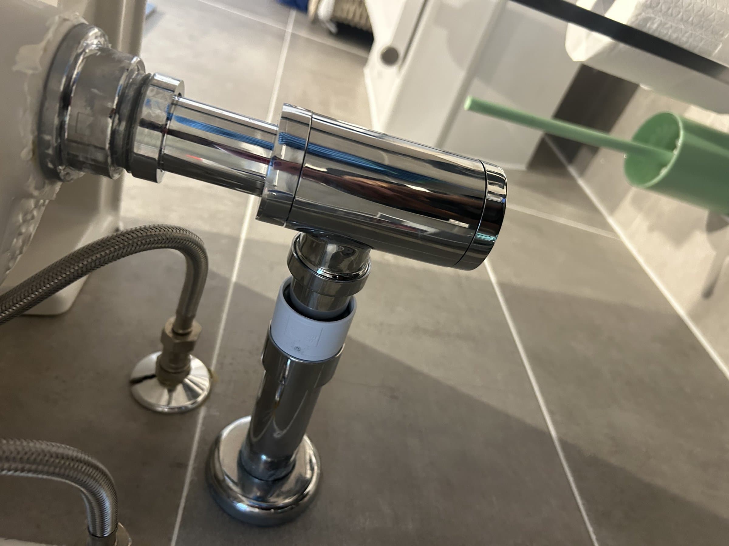 New chrome basin trap and waste pipe fitted under a wall-hung sink