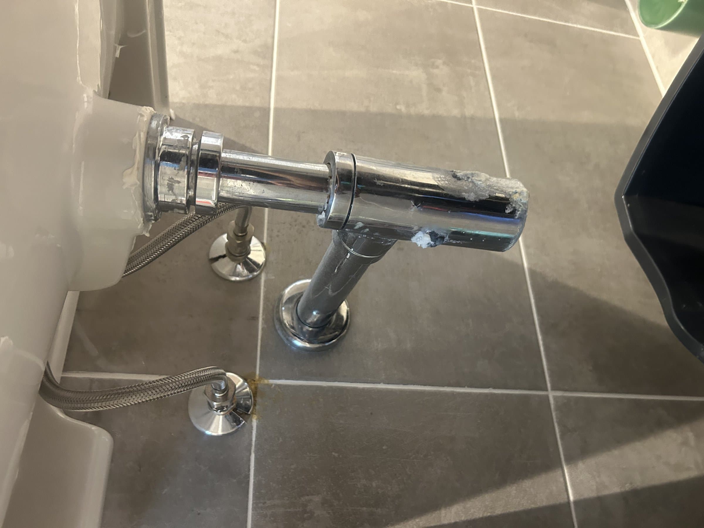 Worn chrome basin trap and waste pipe under a wall-hung sink before replacement