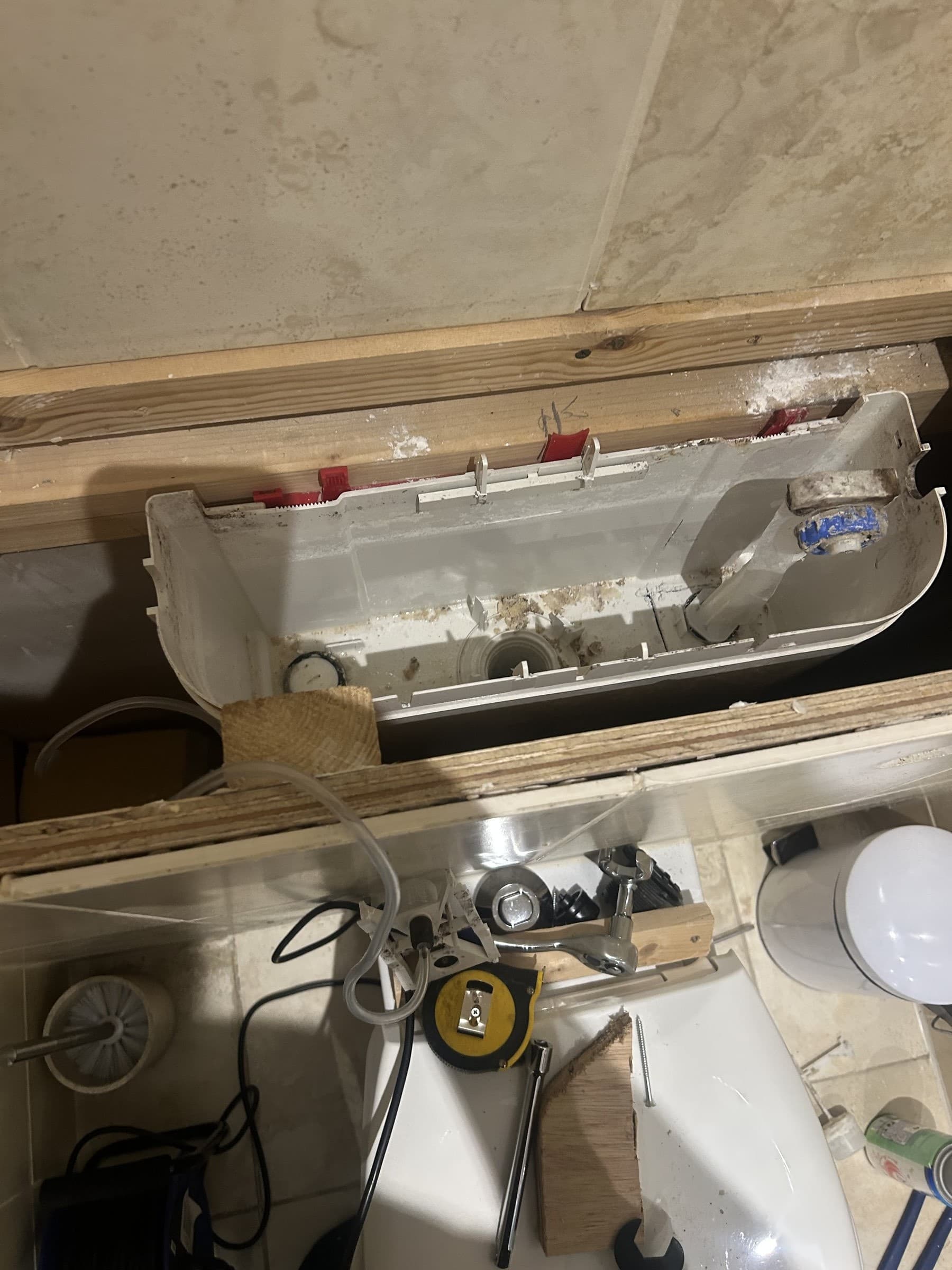 Old, worn concealed toilet cistern exposed inside a stud wall cavity before replacement
