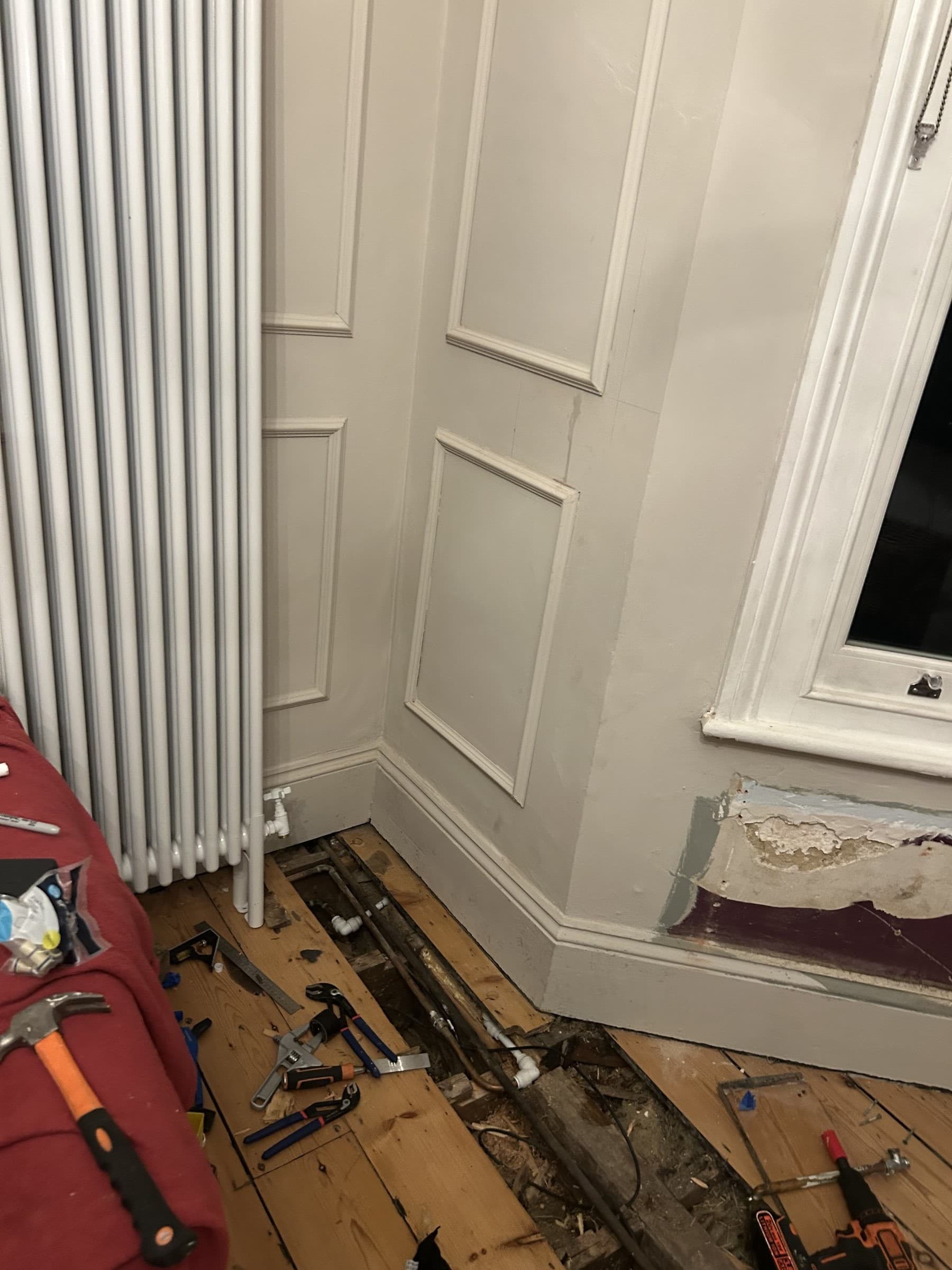 Exposed pipe stub and damaged plaster on a wall before a new radiator is installed