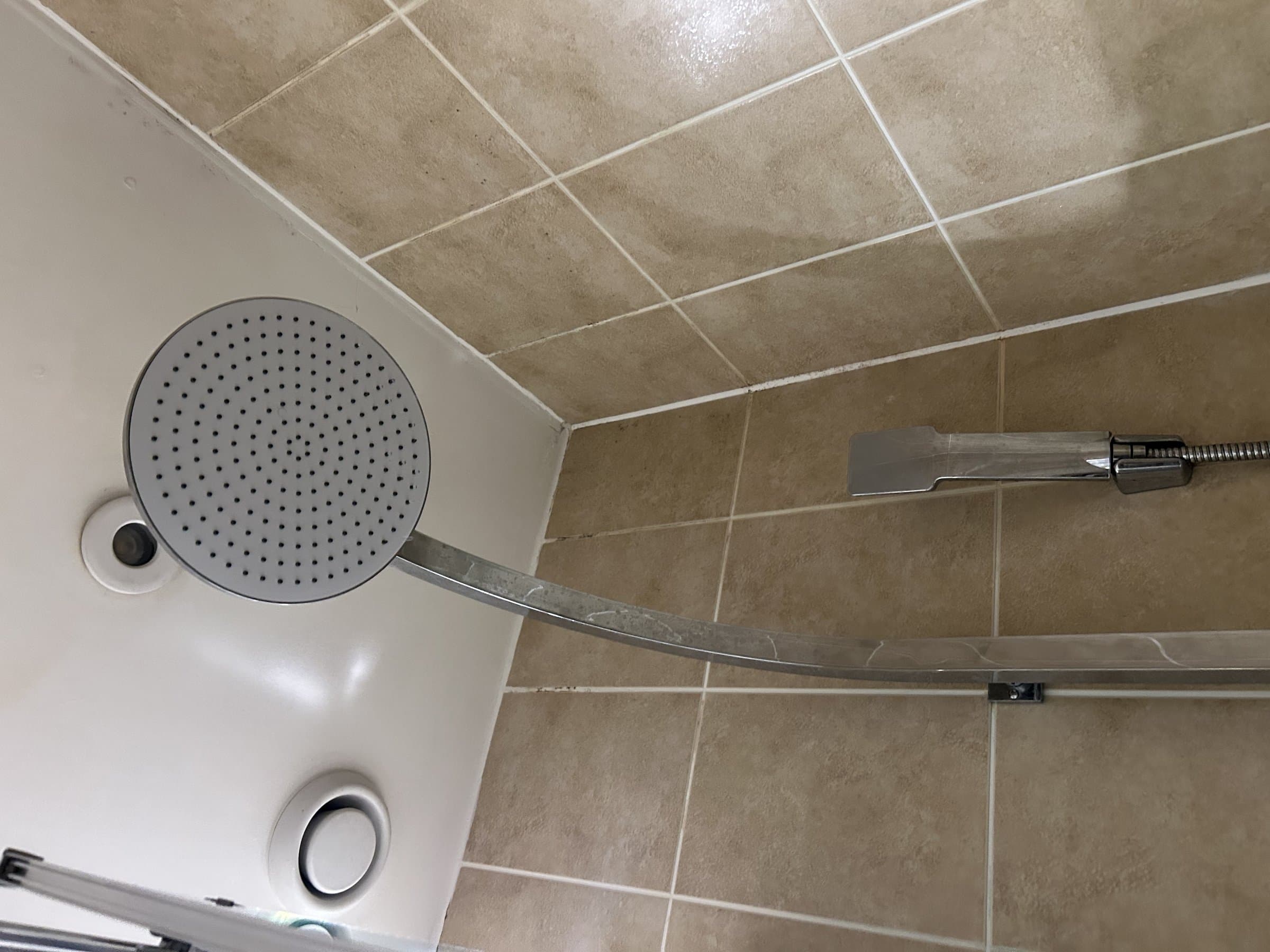 New round shower head and separate handheld shower fitted on a clean tiled wall