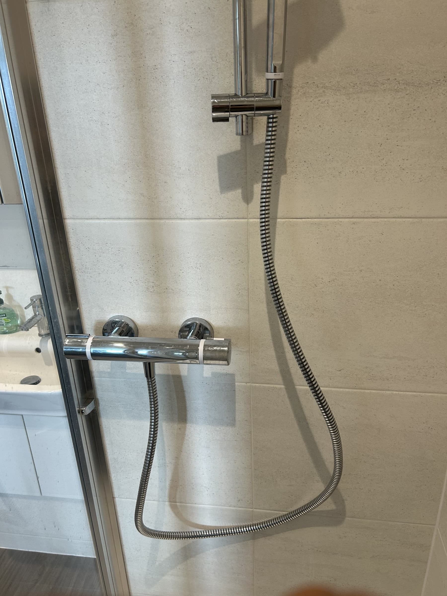 New shower hose fitted and coiled neatly on the shower slide rail