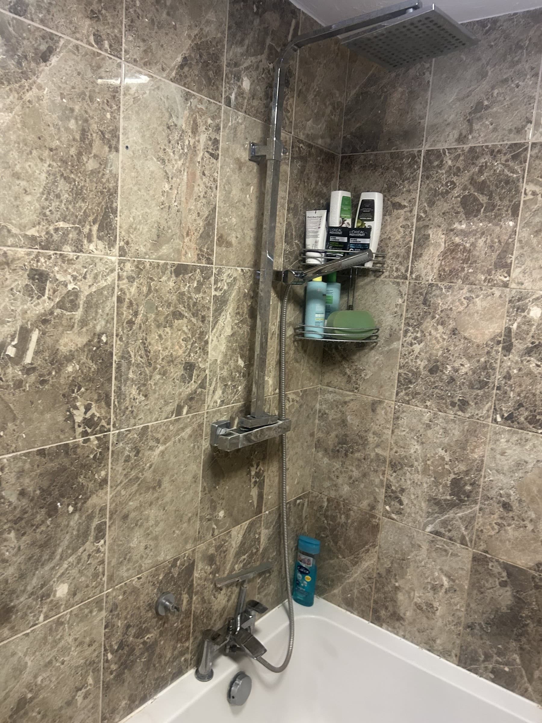 Glass shower screen panel and fitting track laid out on the bathroom floor before installation