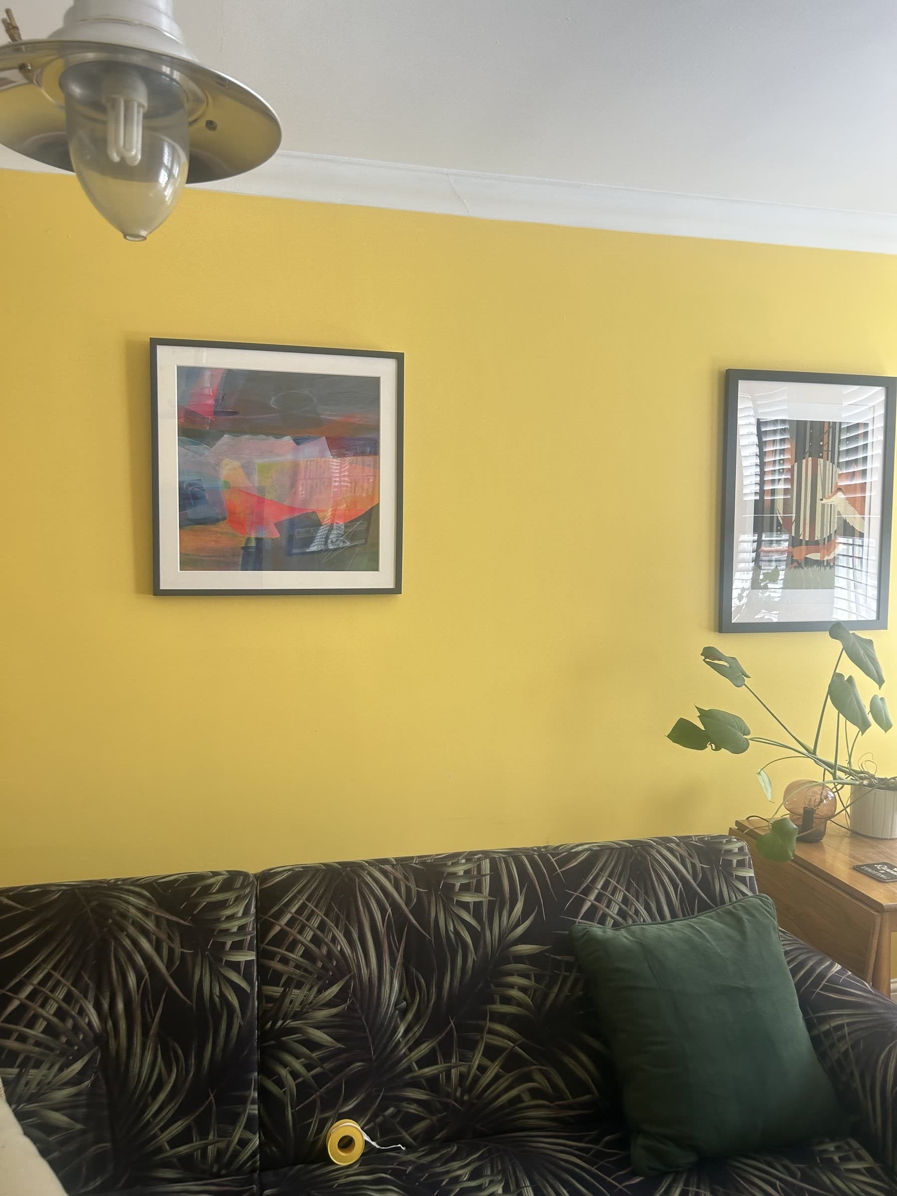 Living room wall with both framed prints hung securely above the sofa
