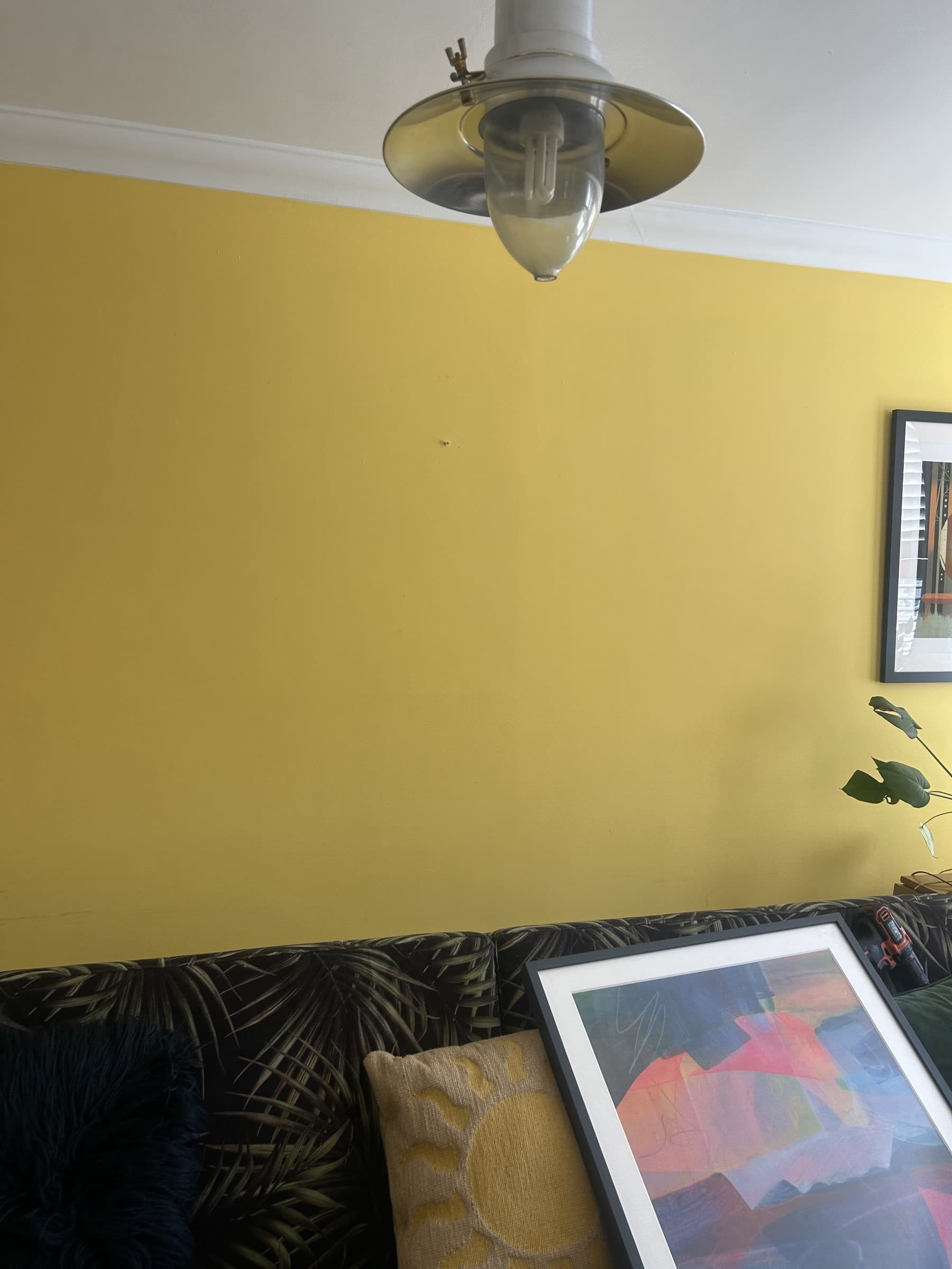 Living room wall with one framed print hung and a second print propped against the sofa, not yet hung