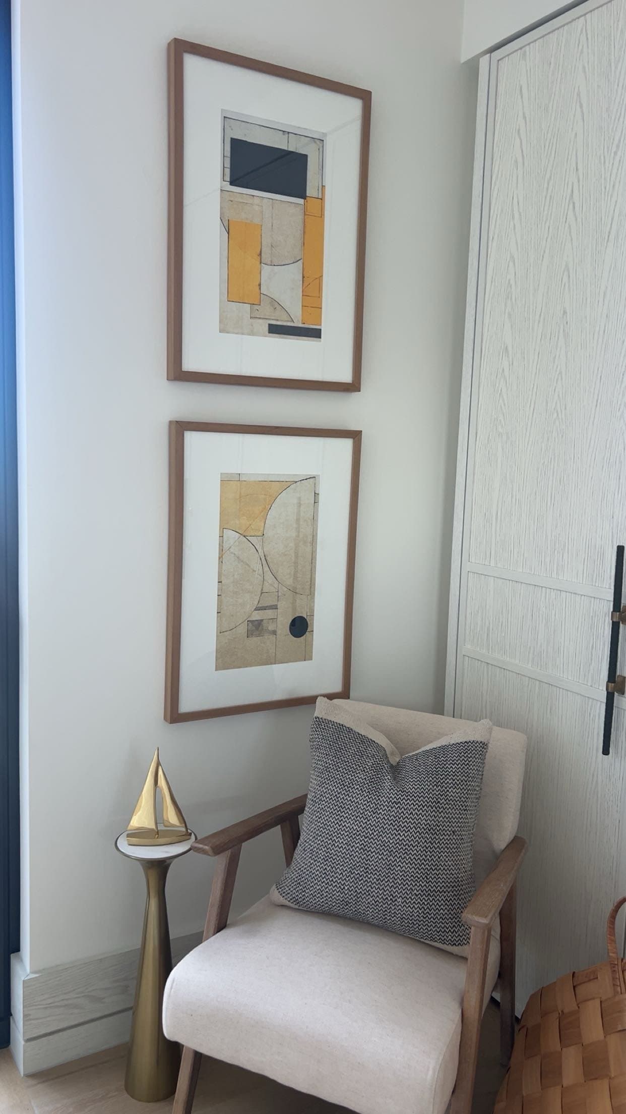 Two framed abstract prints hung above an armchair in a hallway