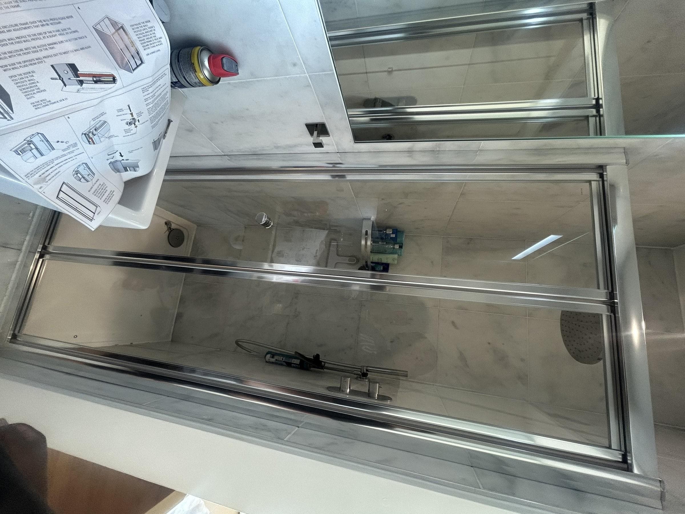 Freshly installed glass shower screen with chrome fittings and overhead rain shower